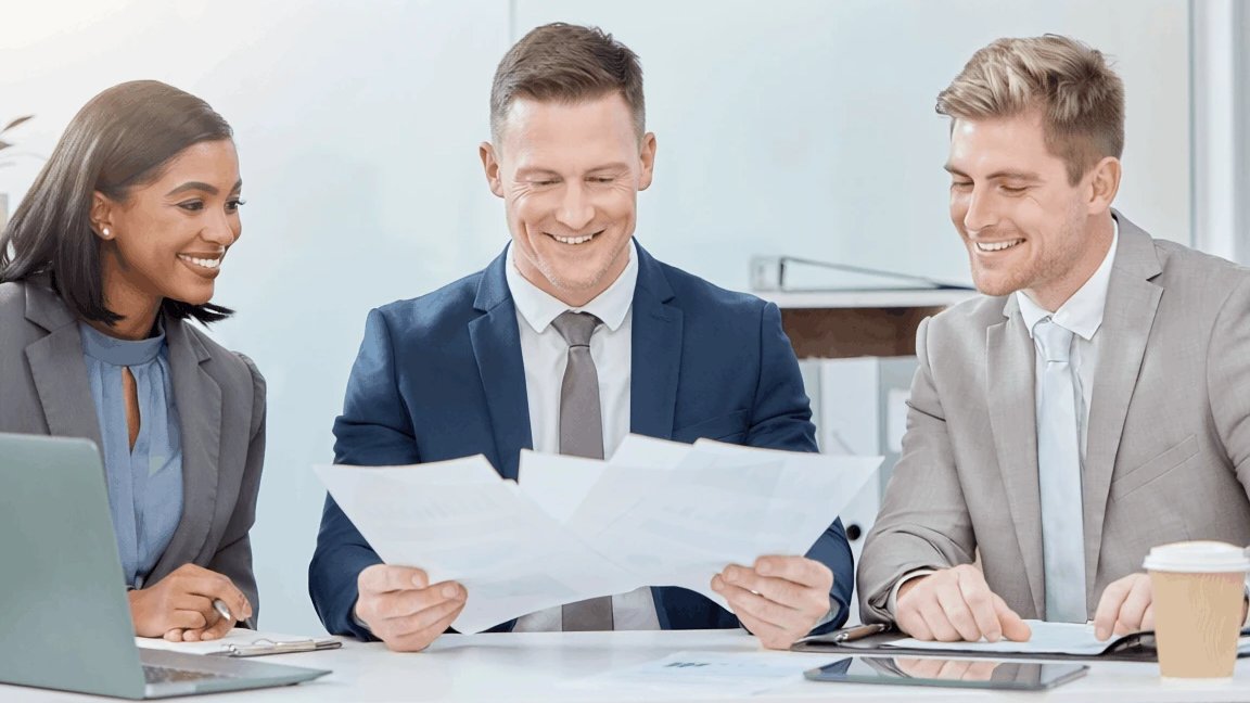 Three business partners reviewing a shareholder agreement together at a meeting table